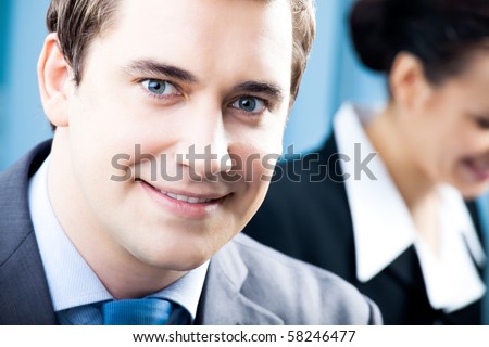 Portrait of successful businessman and colleague on background, at office