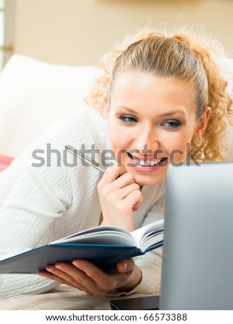 Young happy smiling woman working with organizer and laptop, at home