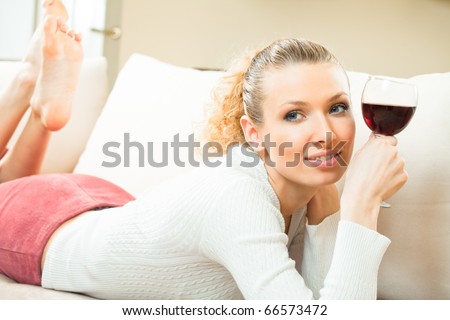 Young happy smiling woman with glass of red wine, at home