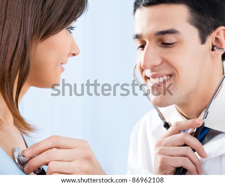 Happy smiling doctor with stethoscope and female patient at office