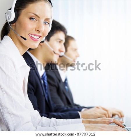 Three happy smiling young customer support phone operators at workplace