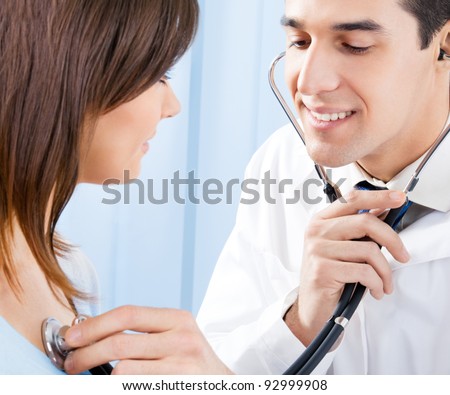 Happy smiling doctor with stethoscope and female patient at office