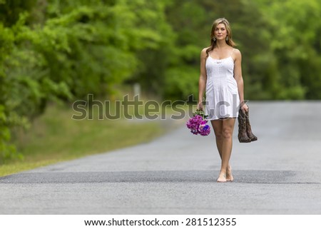 A brunette model walking on a road near a field of flowers
