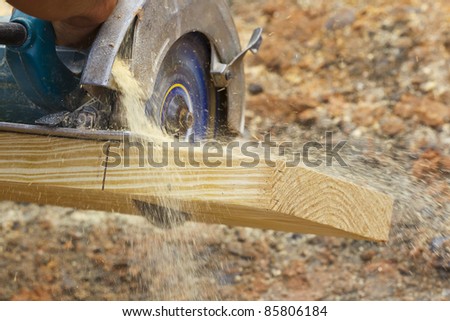 A carpenter cutting wood using a circular saw