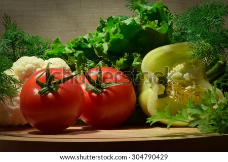 Vegetable set of white pepper, two red tomatoes, salad leafs, parsley and dill branches laid pretty on the table