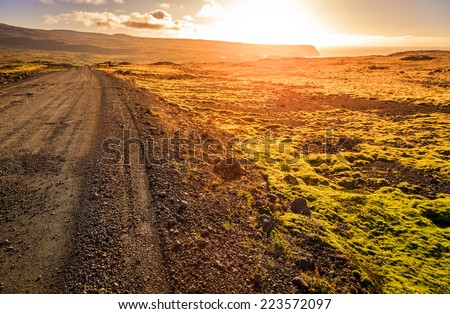 Gravel road through a barren landscape of Westfjords in Iceland