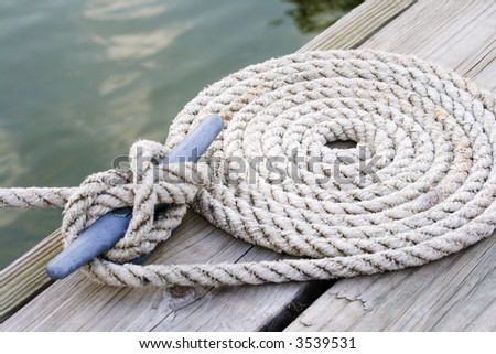 Coiled mooring line tied around cleat on a wooden dock