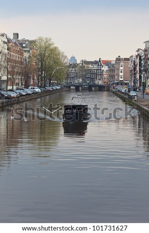 AMSTERDAM, NETHERLANDS - APR 20: Tourist boat cruises on canal in Amsterdam on April 20, 2012. Almost 20 percent of all canal cruise boats are now electrically powered