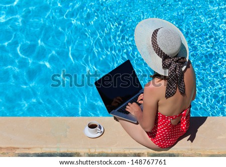 working on vacation concept. Young woman with laptop and coffee near the pool
