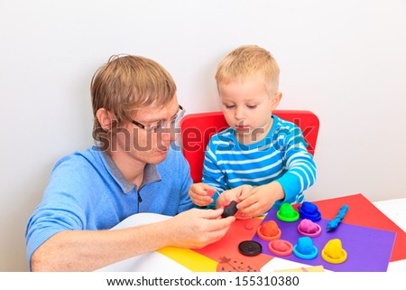 father and son playing with plasticine, early learning and daycare concept