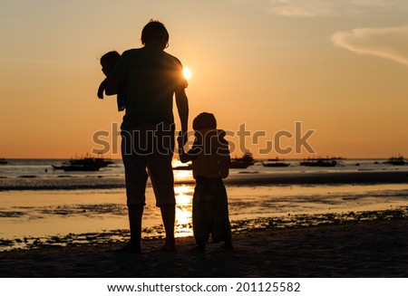 Father and two kids silhouettes on the beach at sunset, family concept