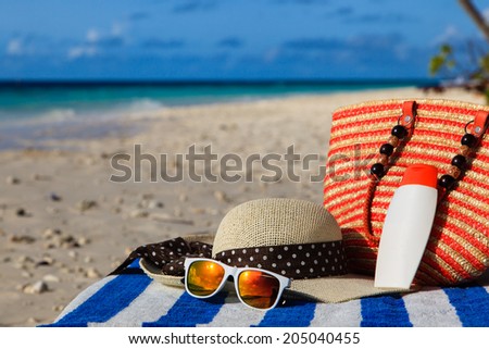 hat, bag, sun glasses and suncream on tropical beach