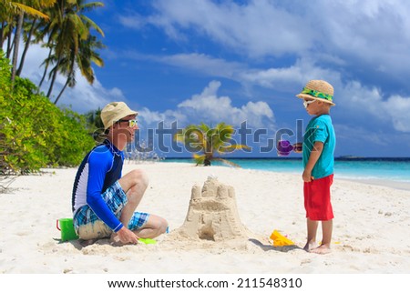 father and son building sand castle on tropical sand beach