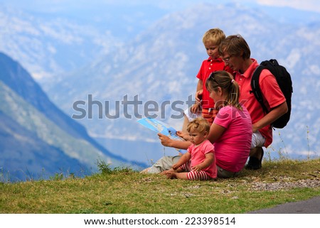 family with kids looking at map in mountains