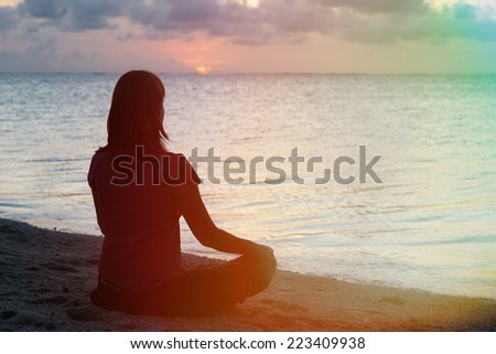 young woman meditation on sunset beach