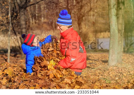happy father and son playing in autumn leaves