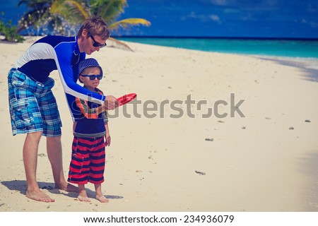 Father and son playing with flying disk at tropical beach
