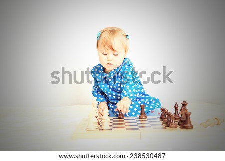 cute little girl playing chess indoors, early learning