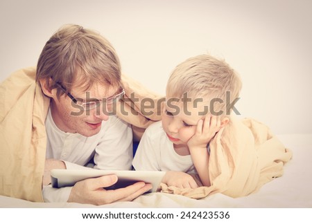 father and little son looking at touch pad in bedroom