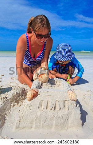 mother and son building sand castle on tropical sand beach