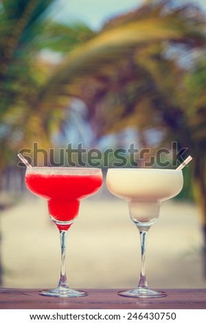 Classic and strawberry margarita cocktails on tropical sand beach