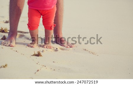 Close up of father and little daughter feet on a tropical beach