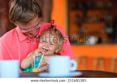 father and little daughter having drink in cafe