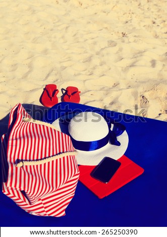 hat, bag, touch pad, mobile phone and flip flops on tropical beach, vacation cocept