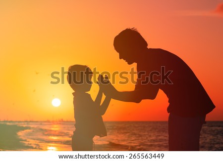 father and son playing at sunset sea