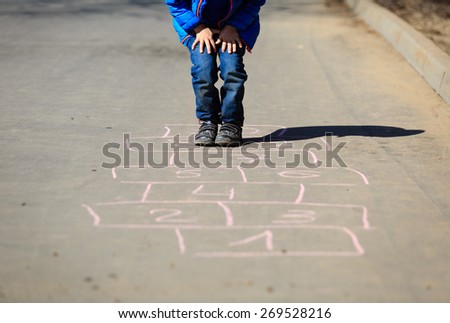 little boy playing hopscotch on driveway outside