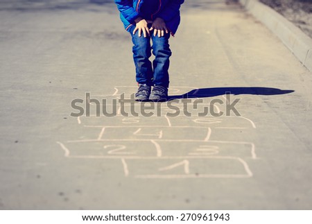 little boy playing hopscotch on driveway outside