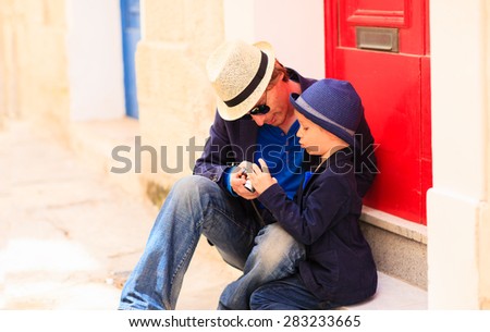 father and son looking at camera on narrow european street, family travel in Europe