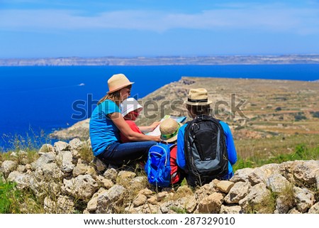 family with two kids looking at map in mountains, family travel