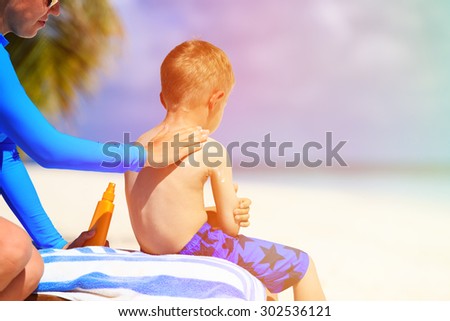 parent applying sunblock cream on son shoulder, sun protection
