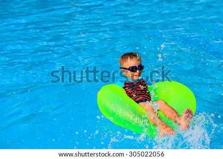 little boy in life ring having fun in the swimming pool