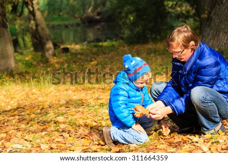 father and little son collecting leaves in autumn fall park