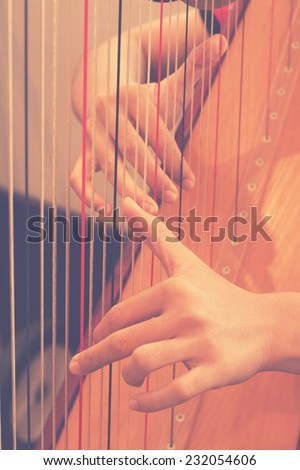 Closeup of a woman playing the harp in rehearsal practice room with retro filter effect lighting or instagram filter
