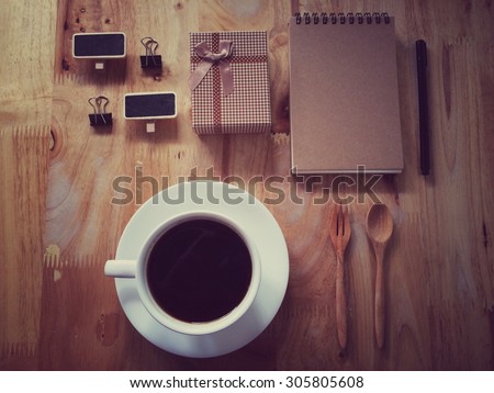 Top view of coffee and stationery mock up set with coffee, paper clip, small black board, notebook and pen in retro filter effect
