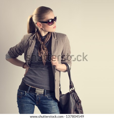 Shopping woman. Attractive young Caucasian fashion girl in sunglasses holding a leather bag and looking aside.