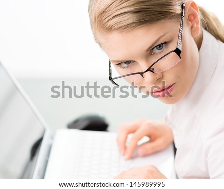 Serious elegant female finding job/ occupation by surfing internet. Cute blonde woman in eyeglasses with laptop.