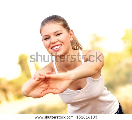 Happy smiling woman runner stretching hands and body in summer forest. Cheerful jogger cross training.