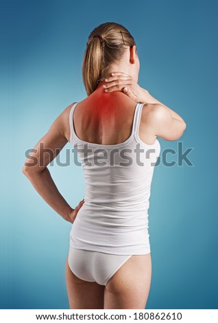 Woman suffer from neck pain, over blue background. Portrait of young girl touching her sick  nape.