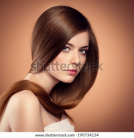 Gentle teenage girl showing her healthy long straight hair. Beautiful Caucasian female model with perfect glossy hair posing in studio.
