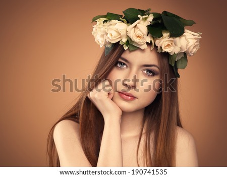 Lovely teenager girl with beautiful rose flowers in her hair. Young attractive female model with professional make-up and beautiful healthy long hair.
