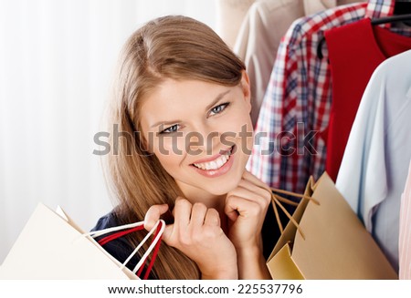 Close up portrait of happy woman buyer holding shopping bags in clothing store. Young beautiful female model happy with seasonal sales.