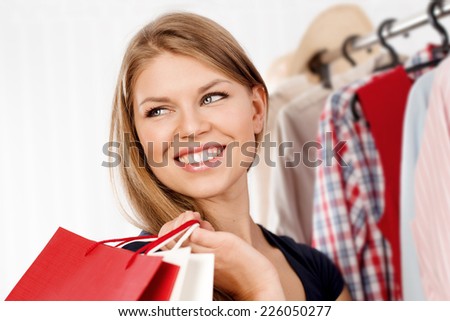 Close-up of lovely blond female shopaholic with colorful bags. Young pretty smiling woman buying clothes in shopping mall.