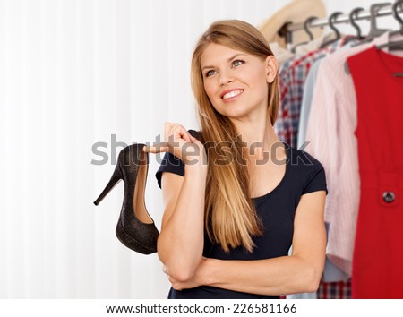 Smiling woman shopper choosing modern shoes in the store. Lovely Caucasian female model buying footwear in shopping mall.