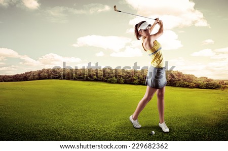 Active woman player hitting the ball on golf court. Sporty female exercising golf play on nature over beautiful landscape background.
