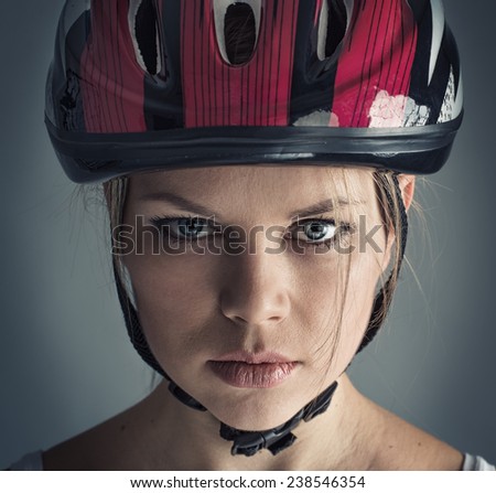 Close-up portrait of young female cyclist wearing safety helmet. Sporty lifestyle and recreation concept.