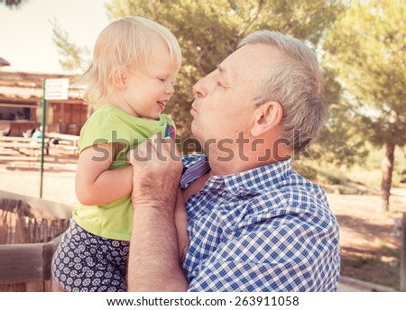Portrait of grandfather with little cute girl having fun on nature in summer. Happy family life concept.